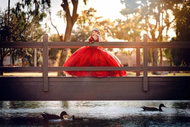 Quinceañera in a red gown on a bridge